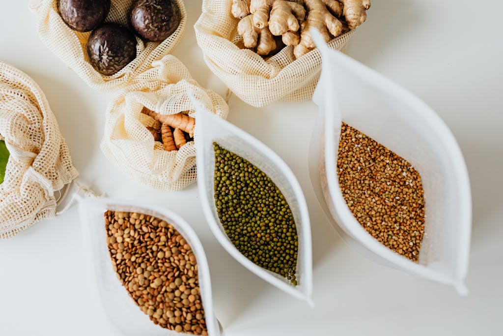 Top view of eco-friendly reusable bags with assorted grains and spices on a white surface.