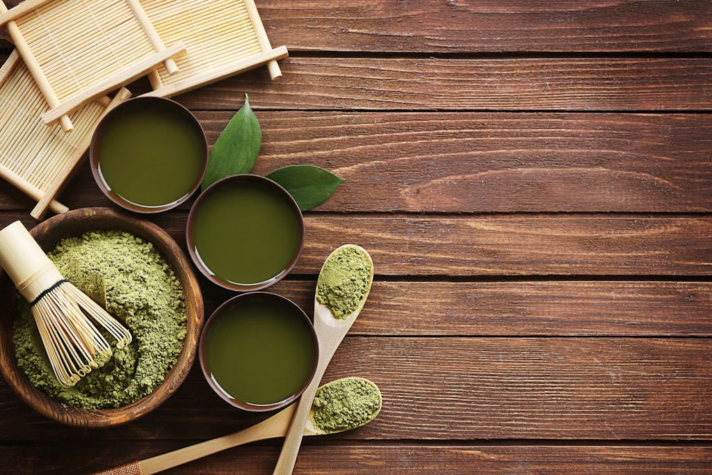 Top view of traditional matcha tea setup with utensils on a wooden table, showcasing a blend of culture and flavor.